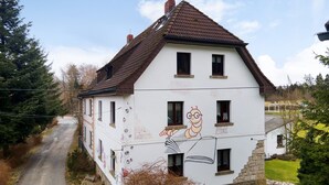 A two-story house with a sloped roof, multiple windows, and a mural on the side. - Apartment "Buchhaus Vier - Mittelgeschoss" with Shared Terrace & Wi-Fi (Kirchenlamitz)