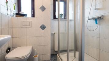 A bathroom with a toilet, a shower, and a window.