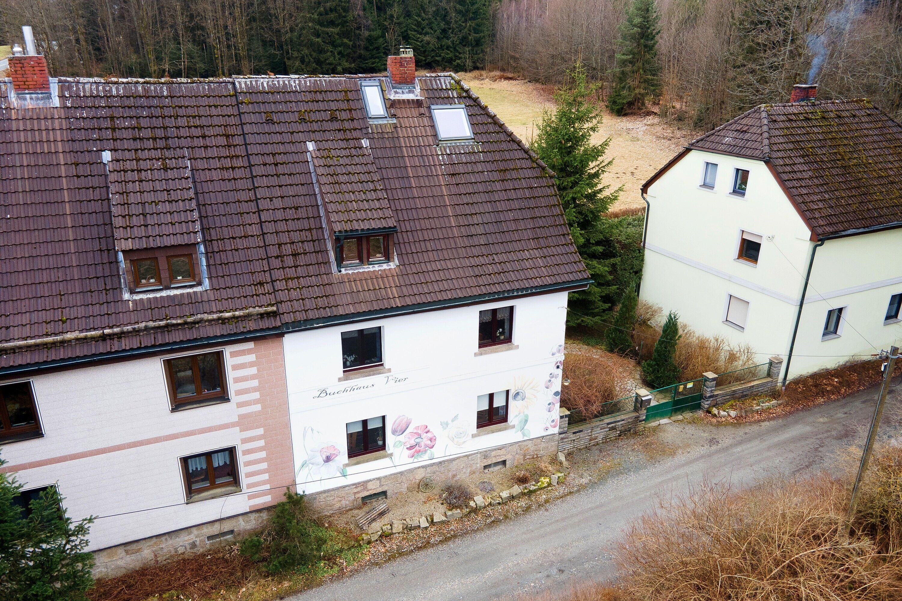 A two-story building with a sloped roof, multiple windows, and a visible chimney.