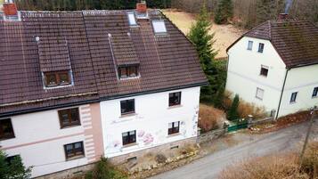 A two-story building with a sloped roof, multiple windows, and a visible chimney.
