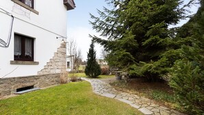 Un chemin de pierres mène à un bâtiment blanc doté d’une fenêtre et d’un mur en pierre.