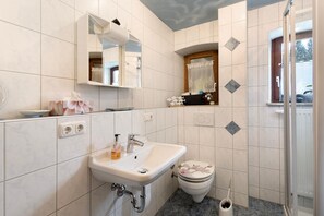 A bathroom with a sink, mirror, toilet, and shower. - Apartment "Buchhaus Vier - Erdgeschoss" with Shared Terrace & Wi-Fi (Kirchenlamitz)