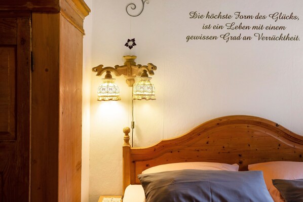 Un lit en bois avec une tête de lit, deux lampes de chevet et un mur orné d’une citation décorative.