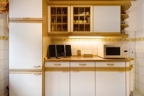 Une cuisine équipée d’un four à micro-ondes, d’une machine à café et de placards aux portes en verre.