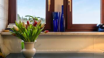 Un jarrón blanco con tulipanes sobre una mesa cerca de una ventana con vistas.