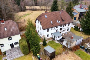 Un quartier résidentiel comprenant une grande maison à deux étages, une dépendance plus petite attenante et un abri de jardin en bois.