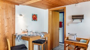 Un interior de madera con una mesa de comedor, sillas, una pequeña zona de cocina con un tostador y una puerta que da a otra habitación.