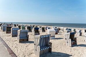 A beach with rows of striped beach chairs and umbrellas.