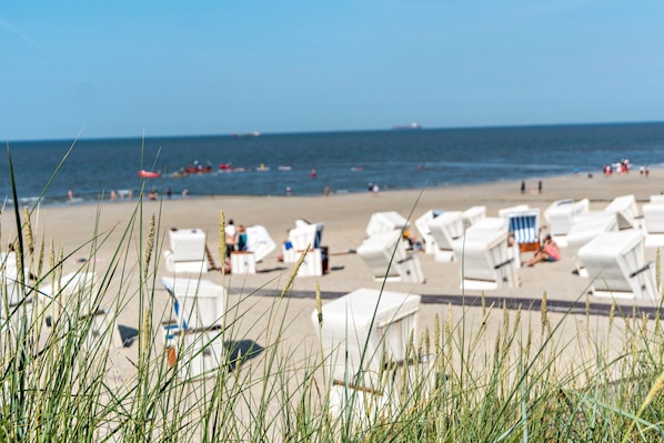 Uma praia com cadeiras de praia brancas e uma faixa de areia.