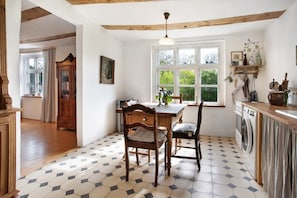 A kitchen with a dining table, chairs, a window, and a washing machine.