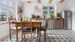 Una cocina con una mesa de comedor, sillas, un refrigerador y una ventana.