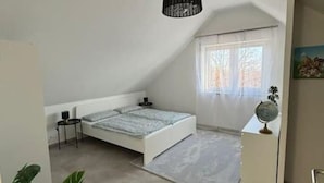 A bedroom with a bed, a hanging light fixture, a window, and a potted plant. - Apartment 'Maisonette Wohnung Frechen City' with Private Terrace, Wi-Fi and Air Conditioning (Frechen)