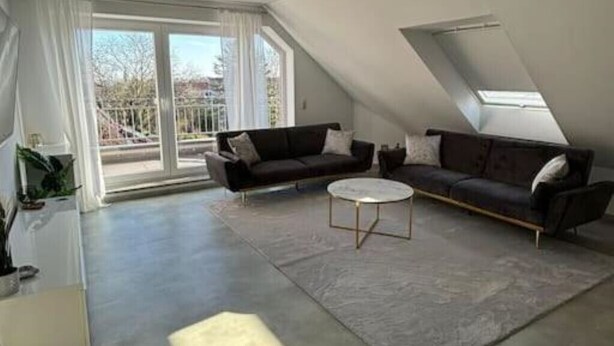 A modern living room with a large window, a sofa, a coffee table, and a rug. - Apartment 'Maisonette Wohnung Frechen City' with Private Terrace, Wi-Fi and Air Conditioning (Frechen)