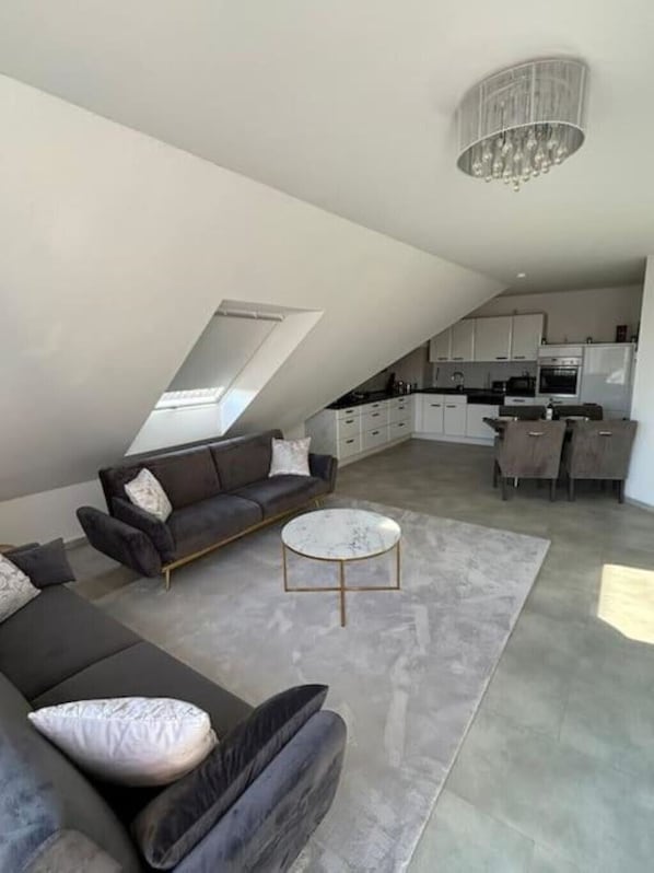 A modern loft apartment with a dining area, kitchen, and a large window.