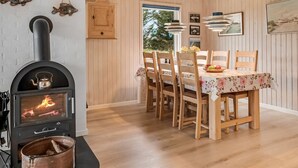 Ein gemütlicher Essbereich mit Holztisch und Stühlen, einem Kamin und Blick ins Freie.