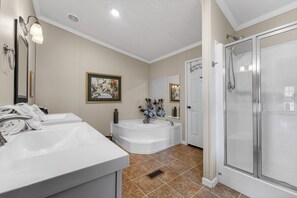 A bathroom with two sinks, a bathtub, a shower, and a door leading to another room.