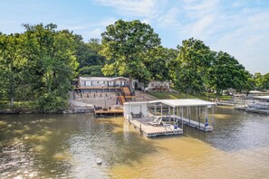 A lakeside property with a dock, a covered seating area, and a building with a deck.