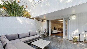 En terrasse med en sofa, et bord og en dør, der fører ind.