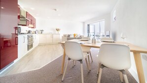 Una cucina moderna con mobili rossi, un'area pranzo con tavolo in legno e sedie bianche, e un'ampia finestra che offre luce naturale.