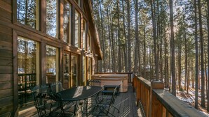 Una terraza de madera con una mesa y sillas, con vista a un bosque.