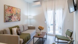 A modern living room with a sofa, a coffee table, a chair, and a painting on the wall. - Pananos Sq House I (Heraklion)