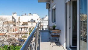 A balcony with a table and chairs, a potted plant, and a view of the cityscape. - Pananos Sq House II (Heraklion)