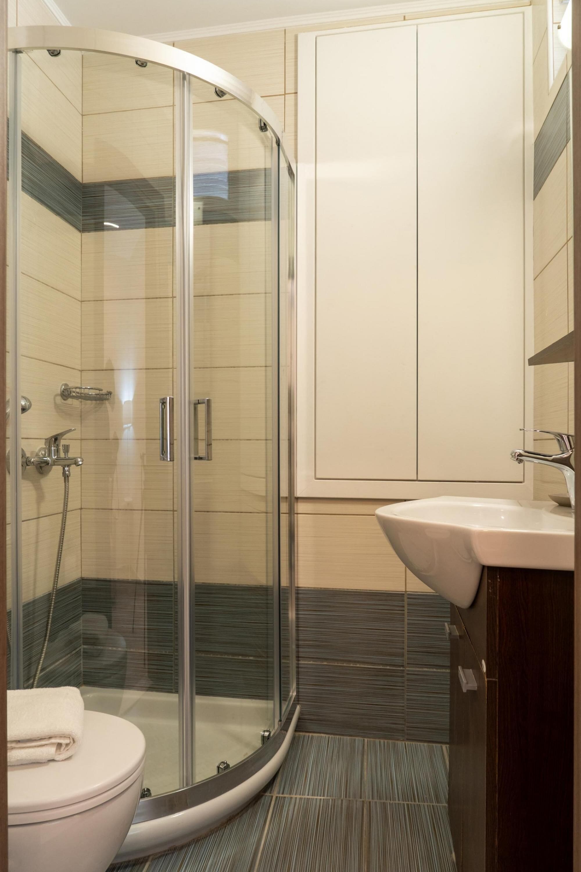 Un baño moderno con ducha envuelta en vidrio, inodoro blanco y lavamanos con espejo.