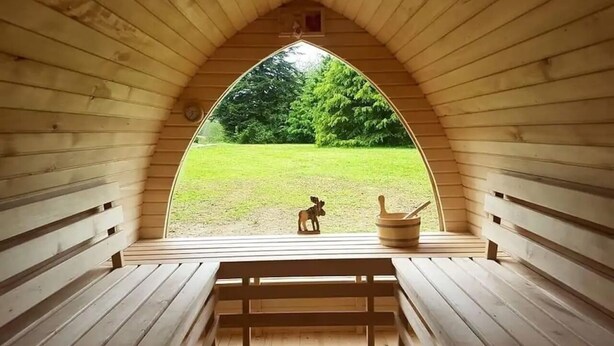 A wooden arched room with a bench and a small table, a window with a view of a grassy area and a tree. - Gîte Chaleureux en Périgord Vert (Sarlande)