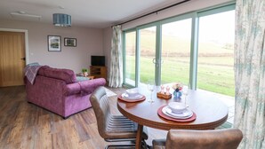 Ein Wohnzimmer mit einem violetten Sofa, einem Esstisch gedeckt mit Tellern, Gläsern und einer Blumenvase.