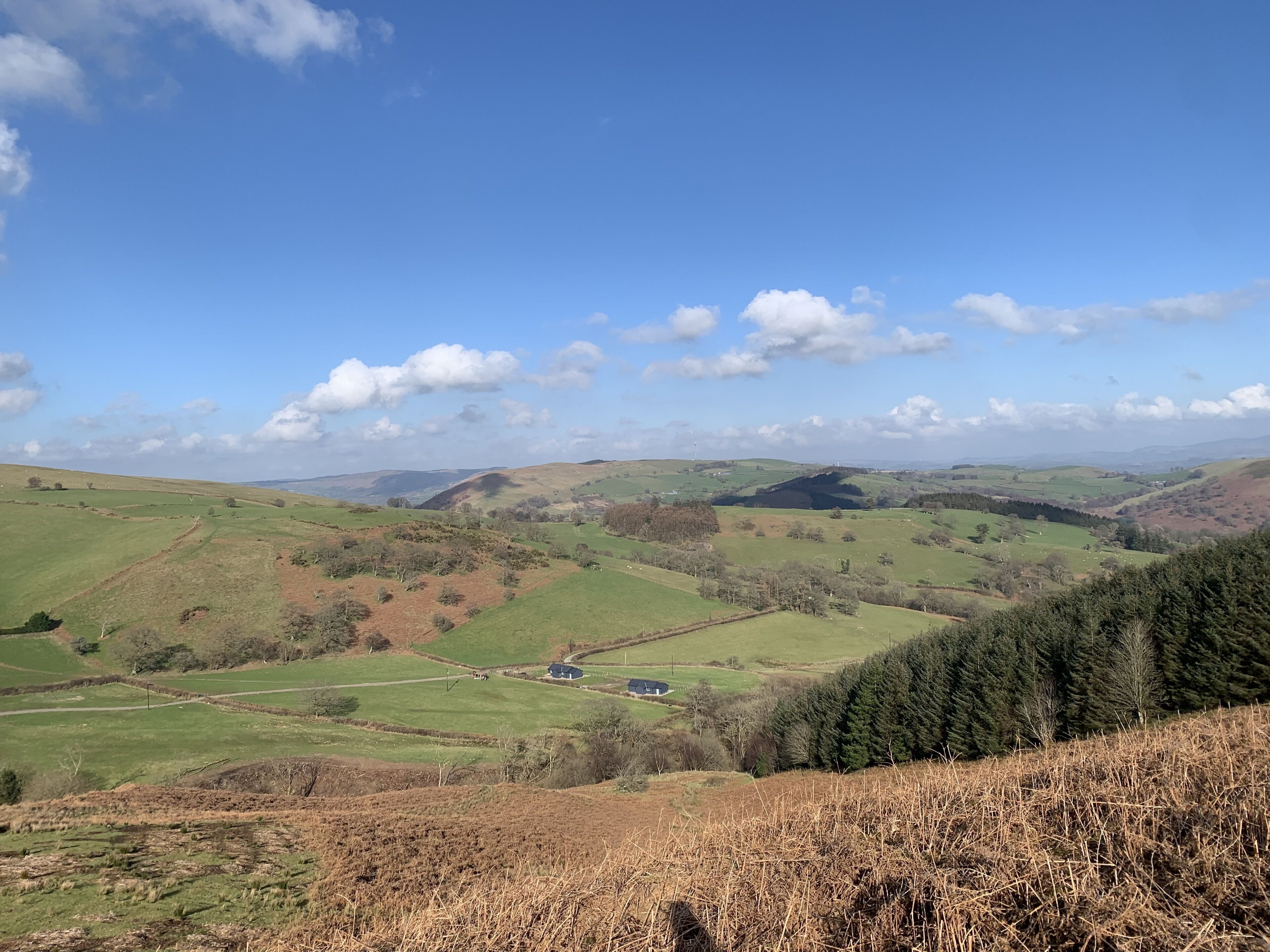 A panoramic view of rolling hills with a small house in the valley.