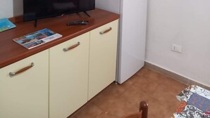 Eine kleine Küchenzeile mit einem Kühlschrank, einem Fernseher und einem Schrank mit Schubladen.