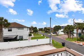 A residential street with houses, a white fence, and palm trees.