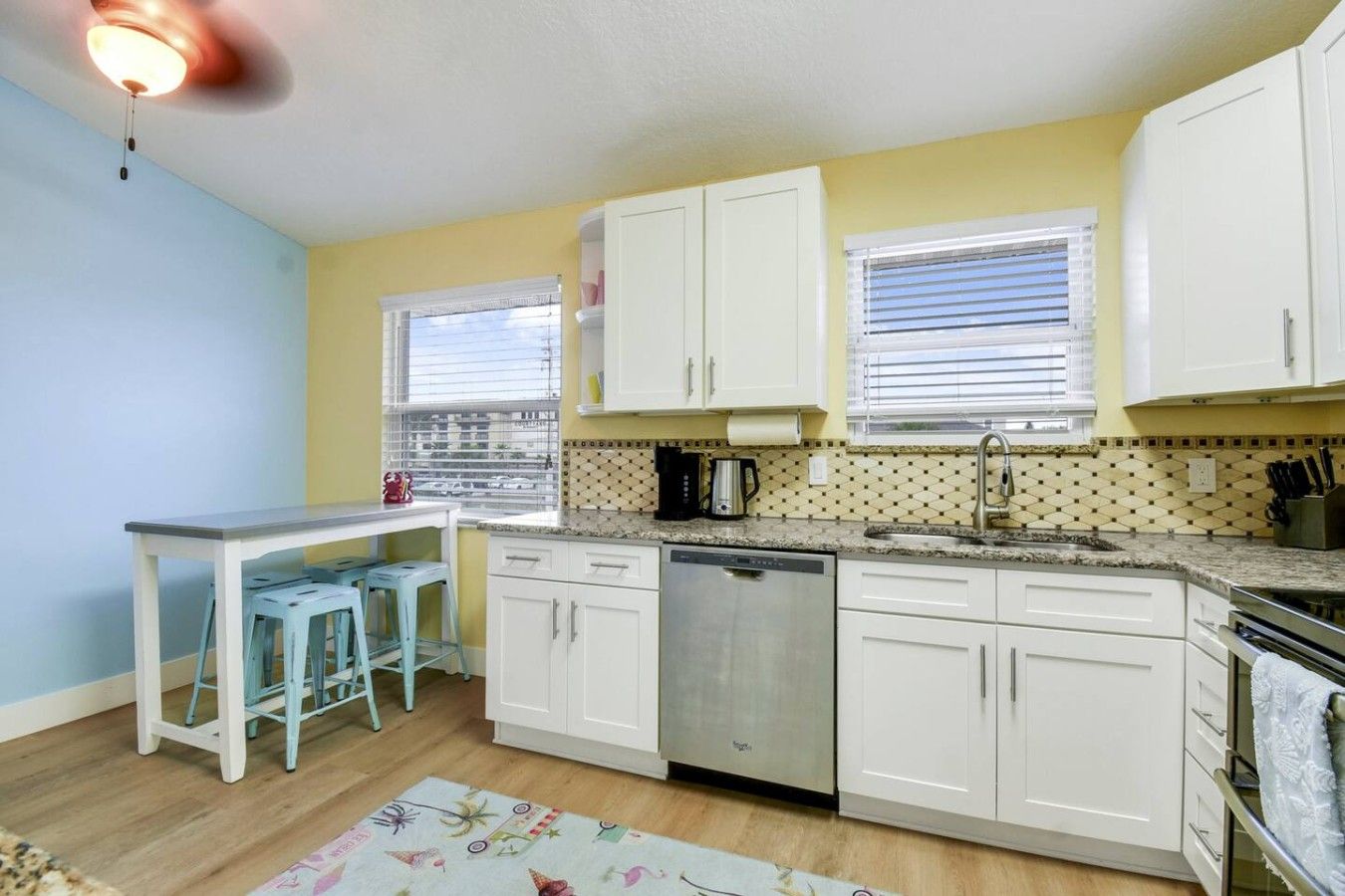 A compact kitchen with white cabinets, a dishwasher, and a countertop with a coffee maker.