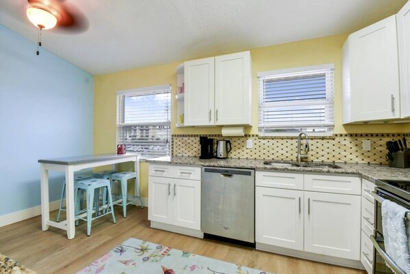 A compact kitchen with white cabinets, a dishwasher, and a countertop with a coffee maker.