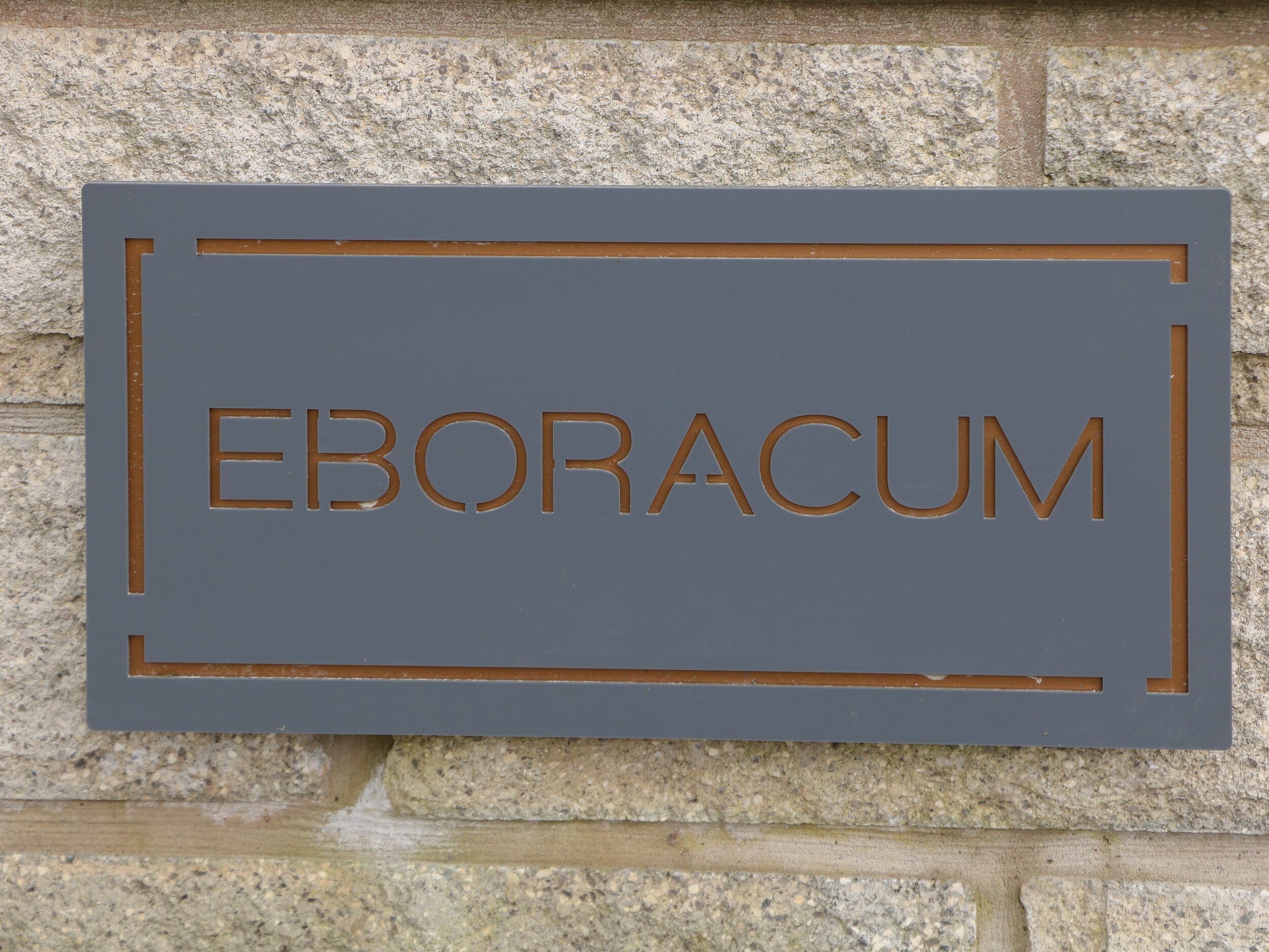 A sign with the word "EBORACUM" on a stone wall.