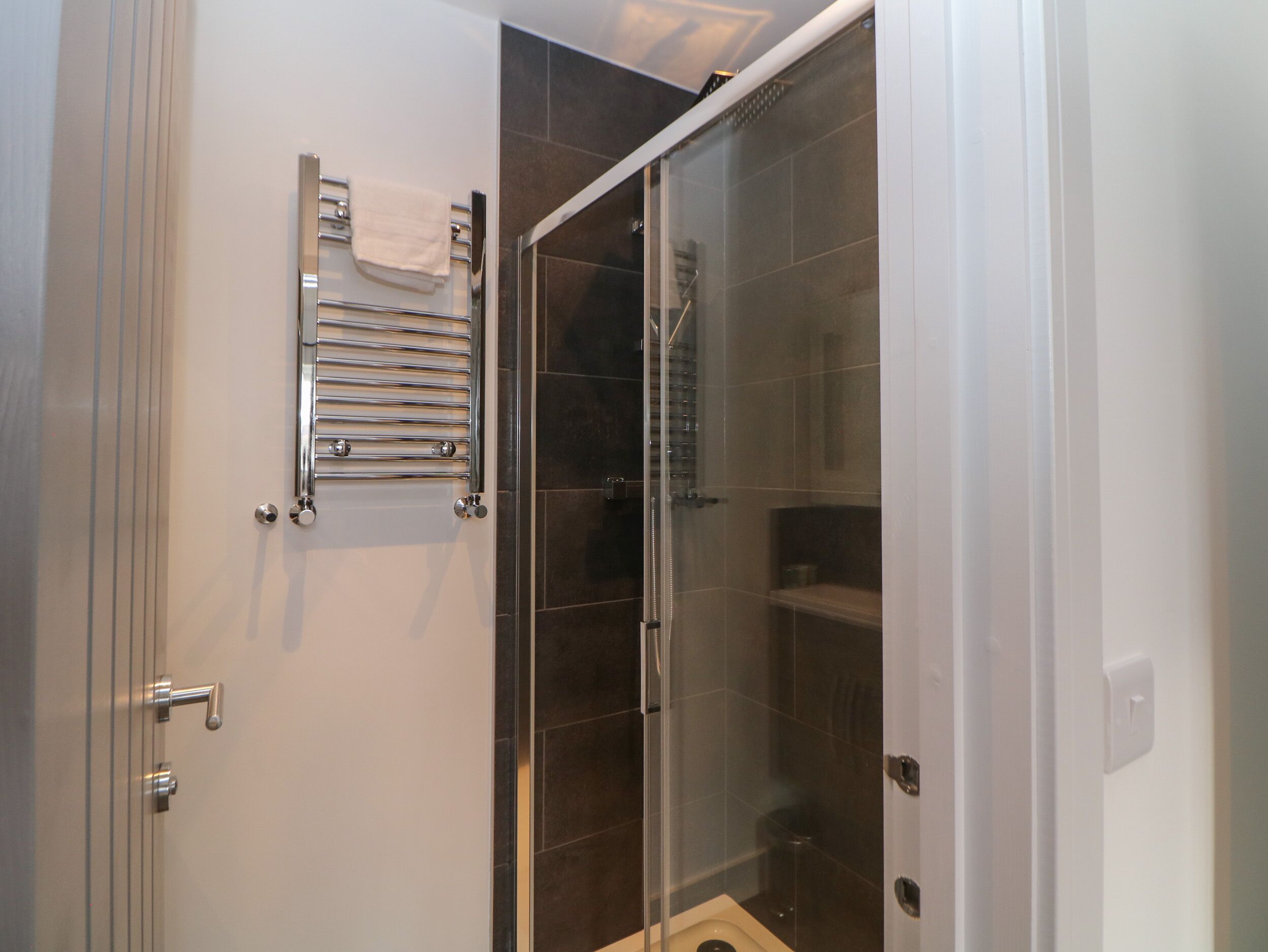 Un baño con cabina de ducha de vidrio, toallero y inodoro.