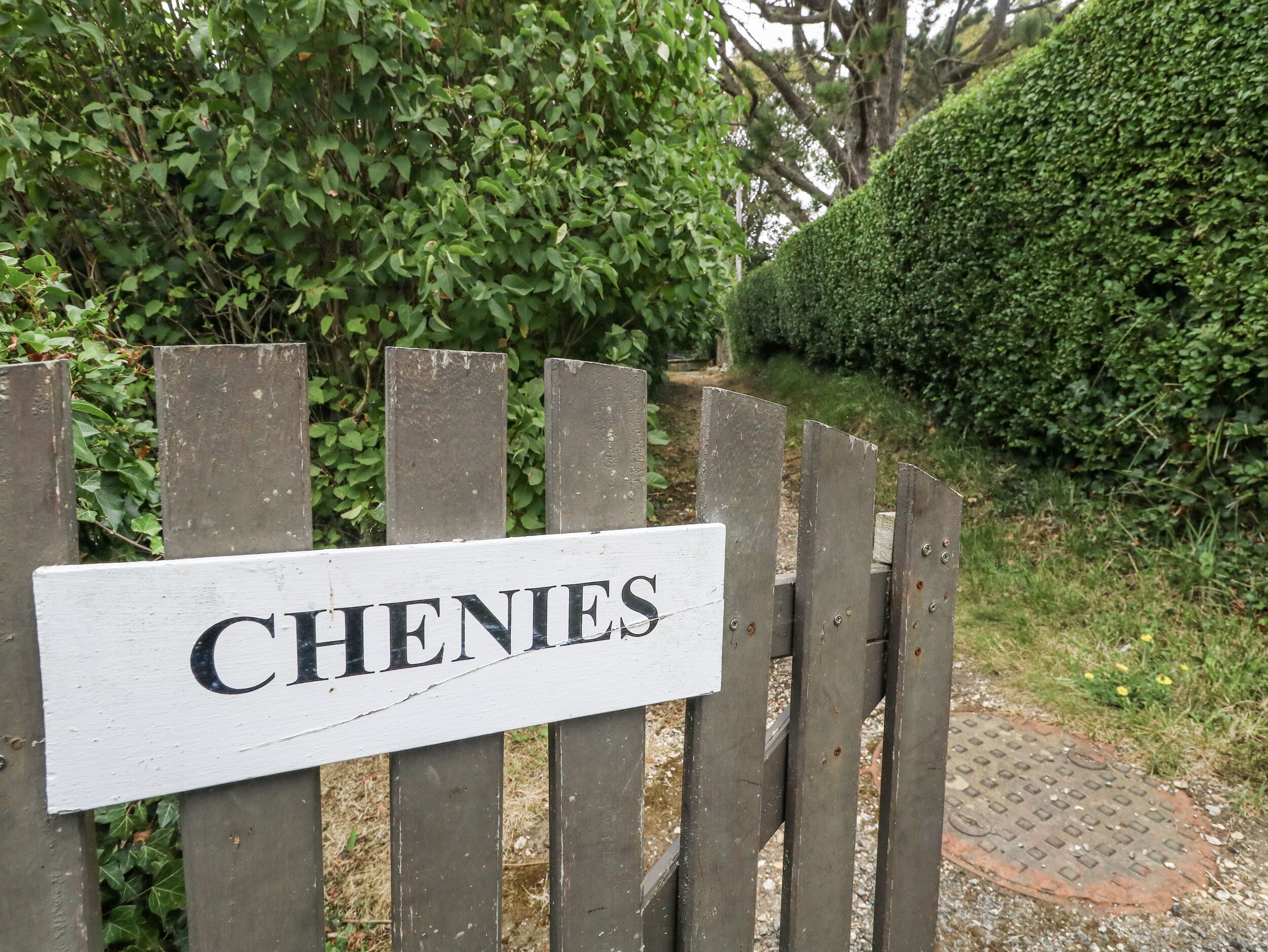 Een houten poort met een bord waarop 'CHENIES' staat.