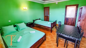 A hotel room with two beds, a dining table, and a wooden wardrobe. - TOKY Hôtel (Antsirabe)