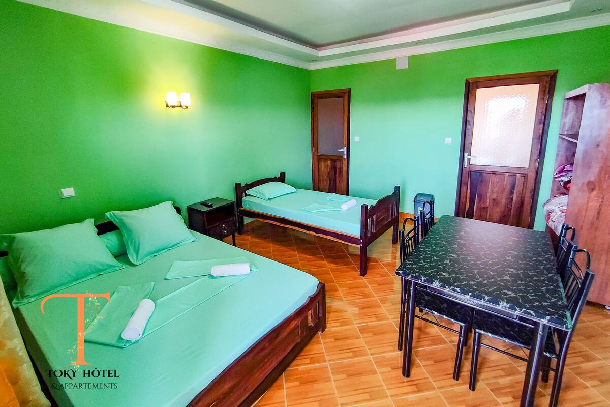 Habitación de hotel con dos camas, una mesa de comedor y un armario de madera.