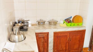 A kitchen with a sink, stove, and wooden cabinets. - TOKY Hôtel (Antsirabe)