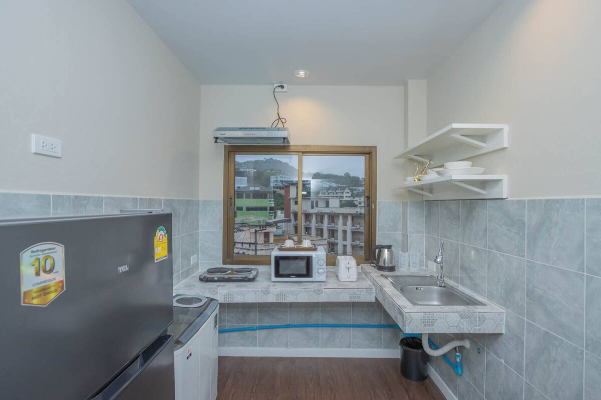 Cocina compacta con refrigerador, microondas, tostadora y pileta. Una ventana da vista a edificios.