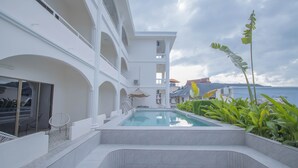 A modern pool area with a clear view of the pool, surrounded by white walls and a balcony.