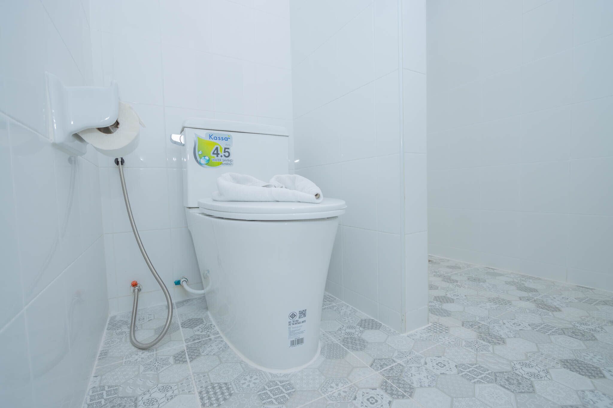 Une salle de bain équipée de toilettes, d’un distributeur d’essuie-tout et d’un flexible de douche.
