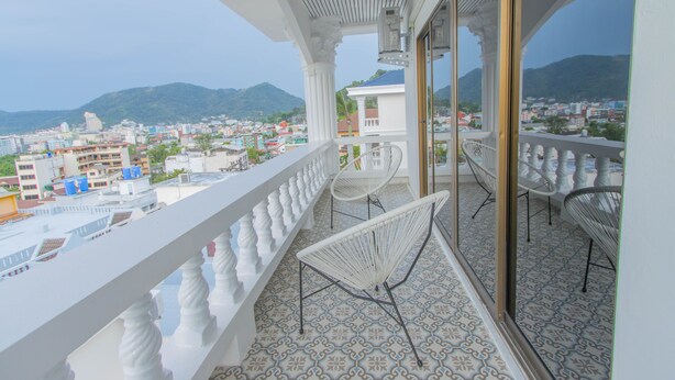 A balcony with a white balustrade, two white wire mesh chairs, and a patterned floor.