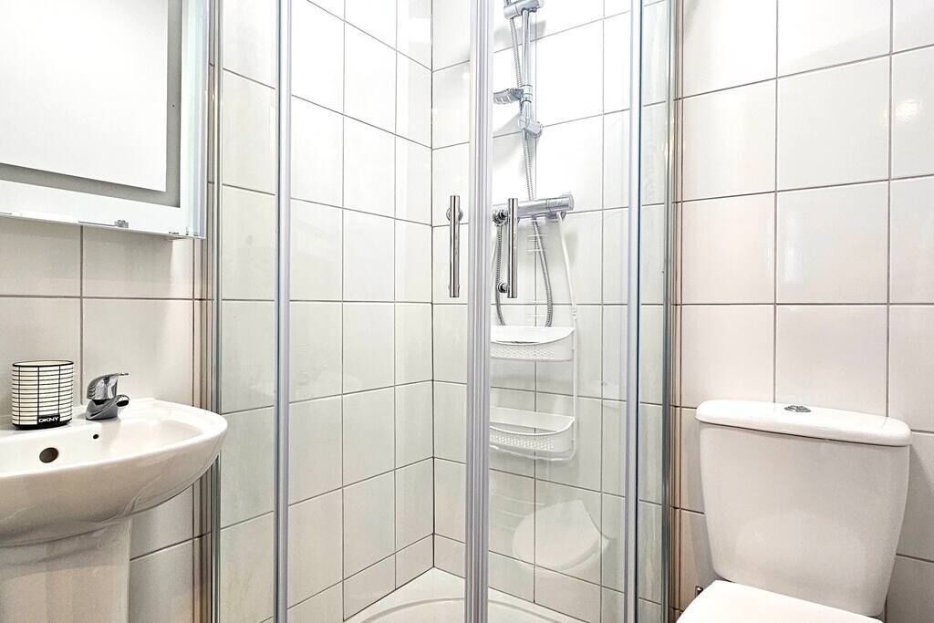Une salle de bain moderne avec une douche à parois de verre, un lavabo blanc et des toilettes.