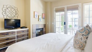 A hotel room with a bed, a television, a fireplace, and a balcony with a view of the outside. - Serene Studio in the Resort-Style Legacy Villas Complex (La Quinta)