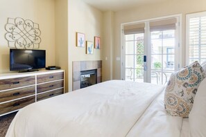 Ein Hotelzimmer mit Bett, Fernseher, Kamin und einem Balkon mit Blick ins Freie.