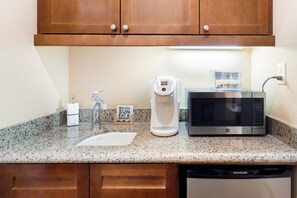 Eine Küche mit Granit-Arbeitsplatte, einer Kaffeemaschine, einer Mikrowelle und einem Geschirrspüler.