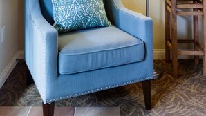 A blue armchair with a patterned pillow, a floor lamp, and a small wooden table in a room with patterned carpet. - Serene Studio in the Resort-Style Legacy Villas Complex (La Quinta)