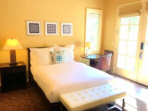 A hotel room with a bed, bedside tables, a chair, and a window with blinds. - Legacy Villas 2Br: PERFECT Spot w/Hotel Luxuries (La Quinta)